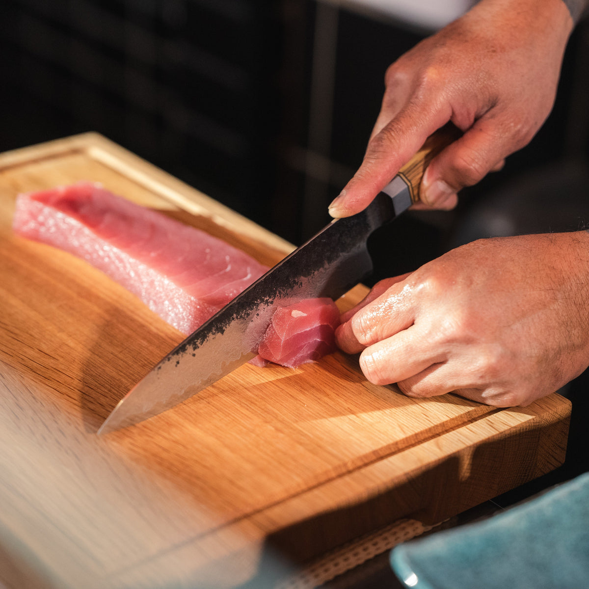 Thunfisch wird mit einem Shōjin Kashi Kochmesser mit Eichengriff auf einem Holzbrett geschnitten