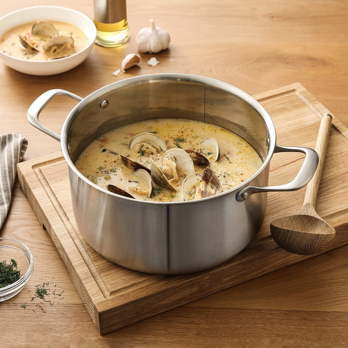 Cremige Muschelsuppe in einem Kochtopf aus 3-Ply Edelstahl auf einem Schneidebrett