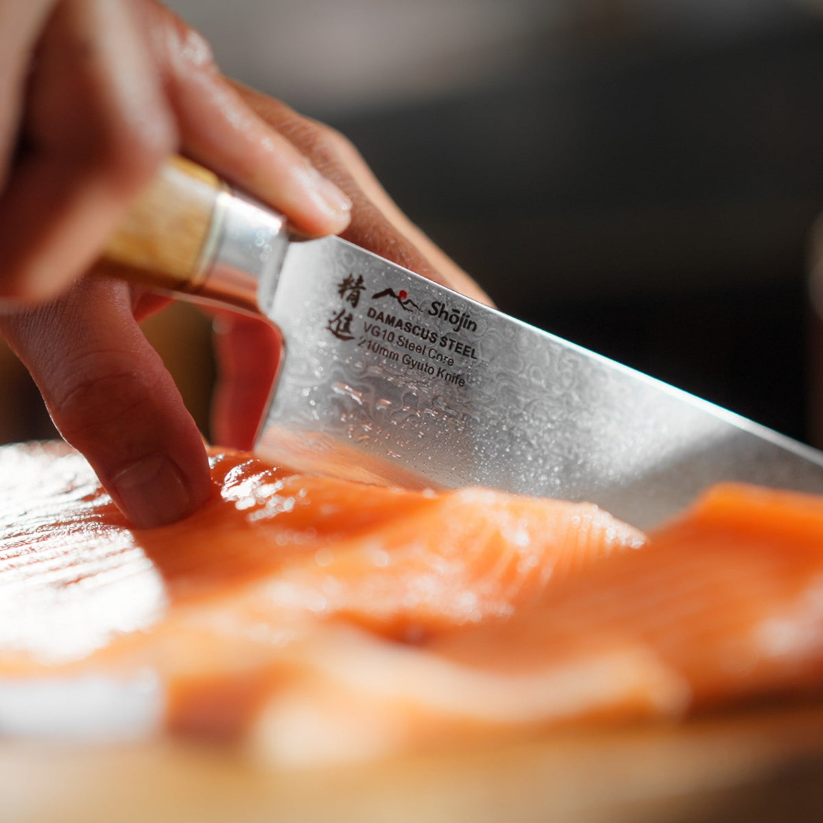 Lachs wird mit einem Shōjin Kaku Gyuto-Kochmesser mit Eichengriff geschnitten, Nahaufnahme
