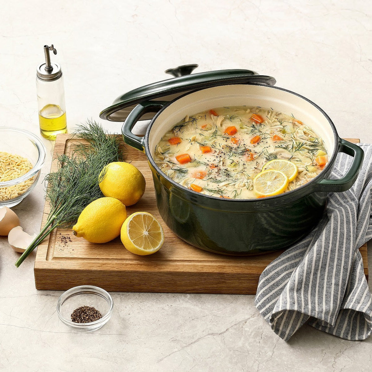 Moosgrüner Gusseisentopf mit Hühnersuppe, Zitrone und Dill, Deckel schräg aufgelegt, auf einem Schneidebrett