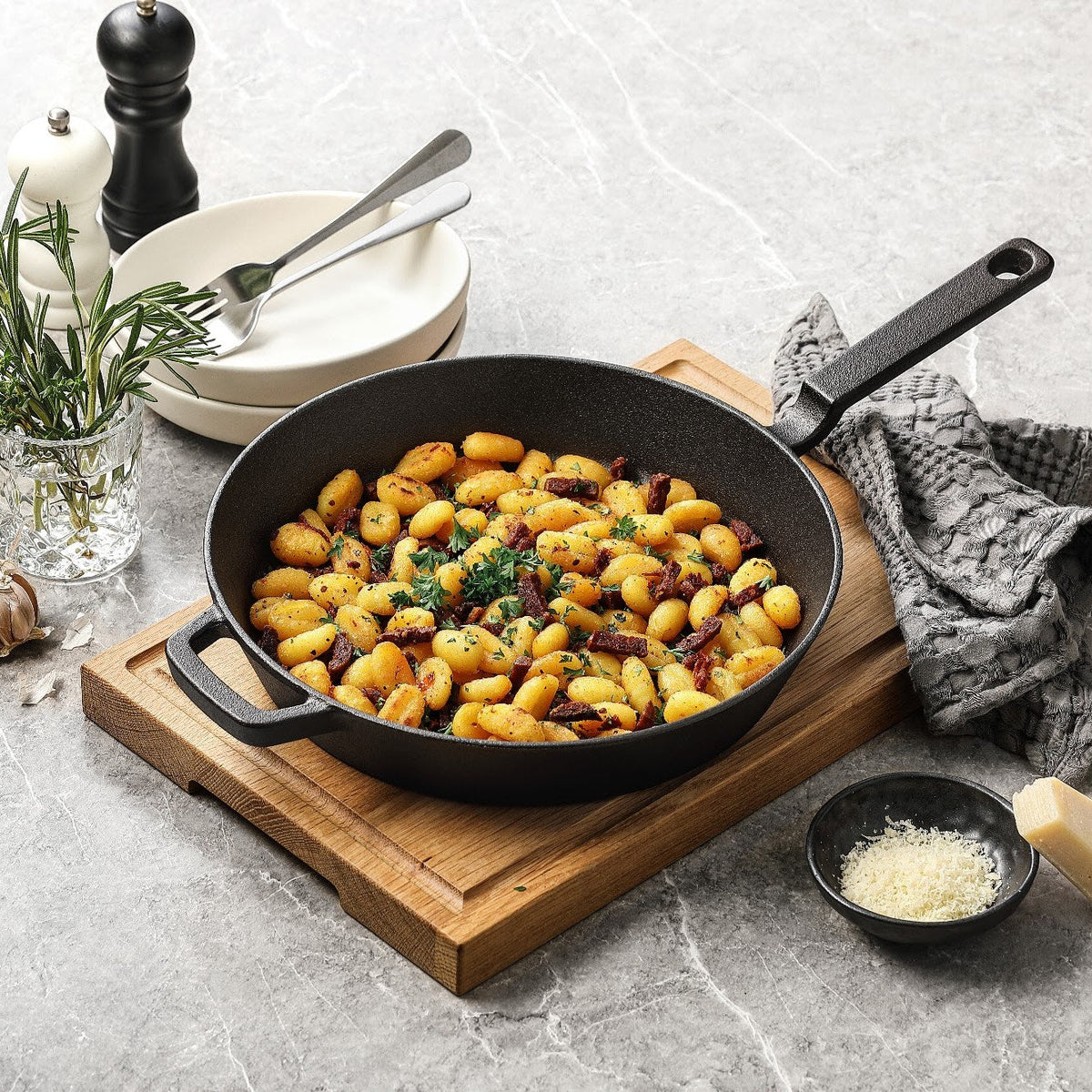 Gusseisenpfanne aus rohem Gusseisen mit gebratenen Gnocchi auf einem Schneidebrett