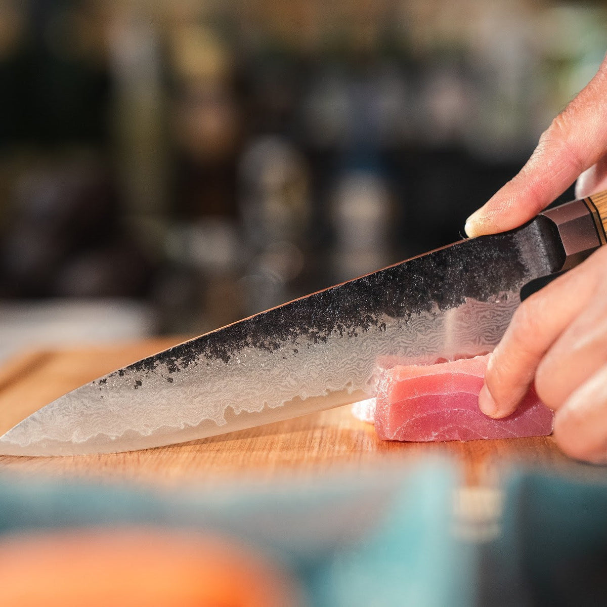 Ein Shōjin Kashi Kochmesser mit Eichengriff schneidet ein Stück Thunfisch, Nahaufnahme